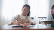© M Stocker - Asian school girl in glasses studying, writing notes in notebook at classroom. Schoolgirl studying and preparing for exams. little pupil writing at desk in classroom. Education knowledge concept
