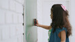 Schoolgirl standing by the board and wiping chalkboard. Kindergarten Asian cute little girl wiping clean or erase chalk on green school board. Back to School. Education concept