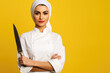 Experienced Middle Eastern Female Chef Showcasing Culinary Skills with a Knife on a Yellow Background - Ample Copy Space for Your Text.




