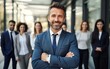 © Kowit - Businessman standing folded hand smile, businessman and businesswoman over big group of businesspeople background
