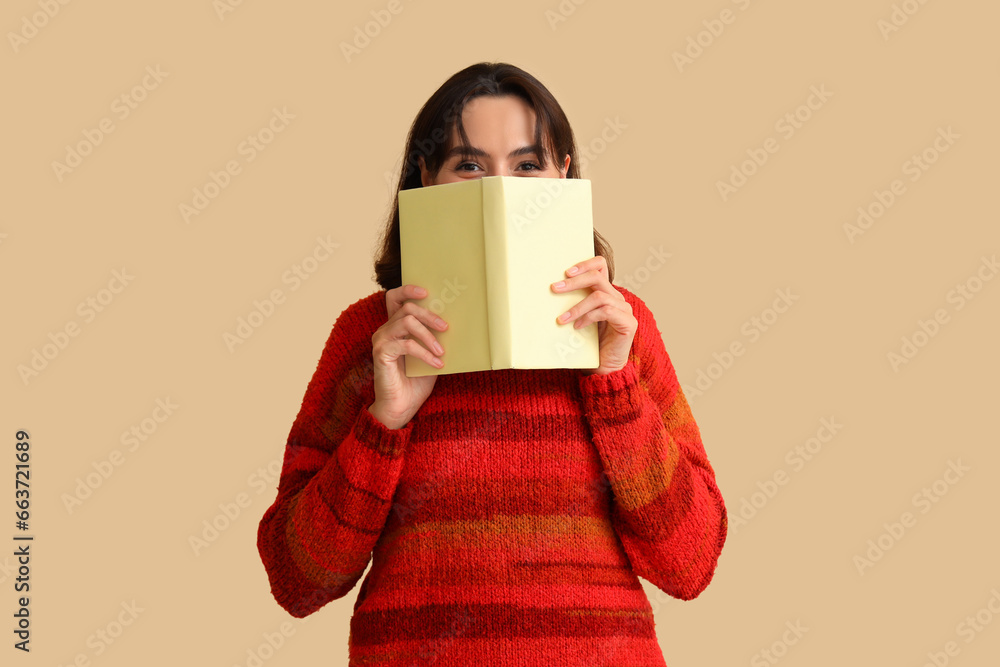 Young woman in red sweater with book on beige background