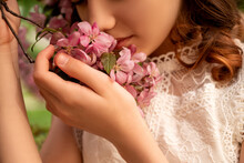 Young Woman Smell Pink Flowers Of  Blooming Apple Tree On Branch In Spring