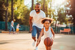 African american dad and daughter playing basketball. Father teaching daughter to play basketball. Family doing sports together and being active.