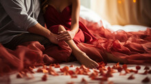 Cropped shot of man touching woman in red dress on bed with rose petals. Romantic couple dating.