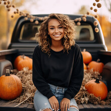 Beautiful Woman Wearing A Black Solid Crewneck Sweatshirt Posing In The Bed Of A Vintage Pickup Truck During Fall Surrounded By Pumpkins, Hay, And Fall Florals