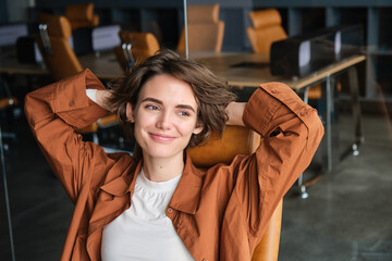 close up portrait of woman at workplace, digital nomad sits back and relaxed in an office, resting a