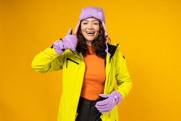 A woman in a warm ski suit on a yellow background.