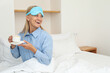 © Atlas - Young woman in sleeping mask drinking coffee in bed