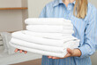 © Atlas - Neatly folded white towels in the hands of a woman