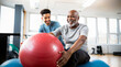 © OpticalDesign - Physical therapist working with elder patient, physiotherapy, helping old retired african american pensioner man in a clinic, therapy