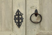 Closeup Of Old Metal Handle And Door Knocker In The Form Of A Ring On Weathered Wooden Door.