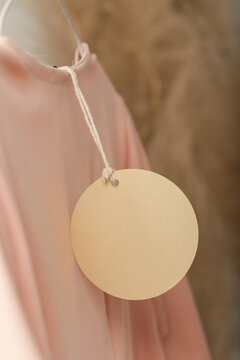 Close up of price tag of clothing item. Blank round label tag mockup on a clothes. Fashion industry and retail concept.	