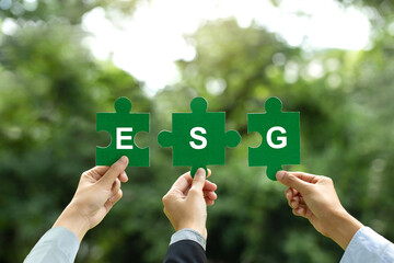 Wall Mural - ESG concept of environmental, social, and governance.Hand of business people holding a piece of jigsaw puzzle with the word ESG to represent collaboration involvement in solving environmental, social