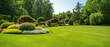 Leinwandbild Motiv Beautiful manicured lawn and flowerbed with deciduous shrubs on plot or Park outdoor. Green lawn closely mowed grass.