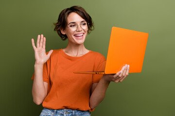 Canvas Print - Portrait of cheerful nice person wear stylish t-shirt eyewear waving hand at laptop on video call isolated on green color background