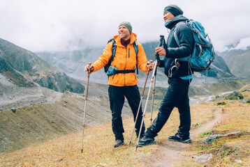 Wall Mural - caucasian and sherpa men with backpacks with trekking poles together smiling enjoying mera peak clim