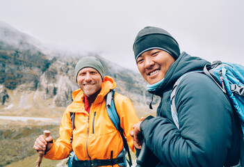 Wall Mural - caucasian and sherpa men with backpacks together smiling at camera makalu barun park trekking route.
