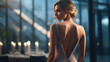 the graceful back of the bride in a white dress with a large cutout on the back, her face turned so that her profile is visible, luxurious hair, she stands in front of a large window