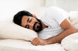 © Prostock-studio - Smiling Young Indian Man Sleeping Calmly In Comfortable Bed At Home