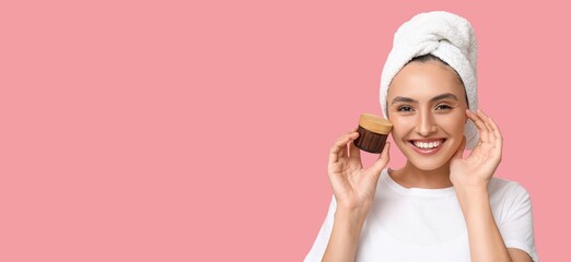 Poster - Beautiful young woman holding cosmetic cream on pink background with space for text