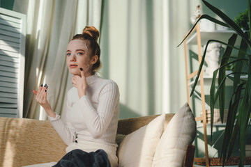 Wall Mural - beautiful young lady sitting on the sofa, enjoying her beauty procedures at home. wellness and wellb