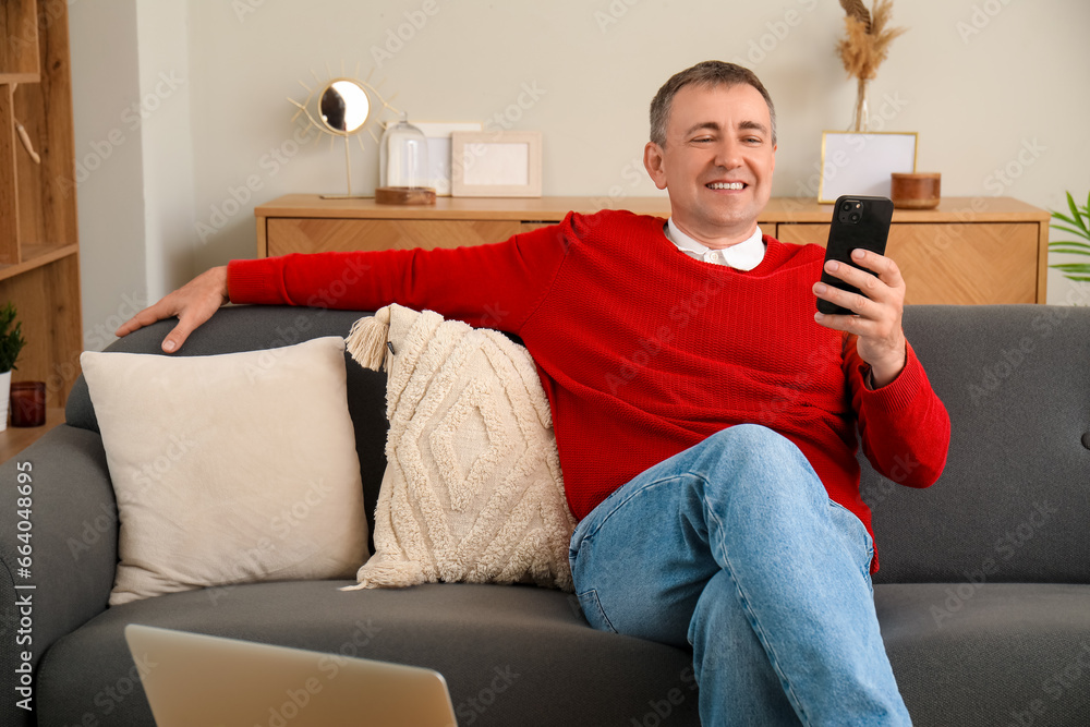 Mature man with mobile phone messaging at home