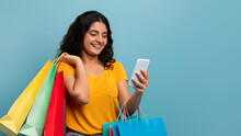 Cheerful Young Indian Woman With Phone And Shopping Bags