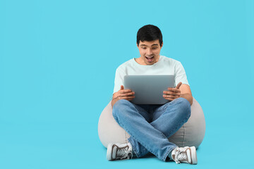 Canvas Print - Surprised male programmer with laptop sitting on blue background