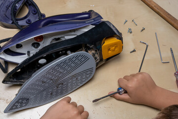 Disassembled electric iron. repairman checking and fixing broken iron