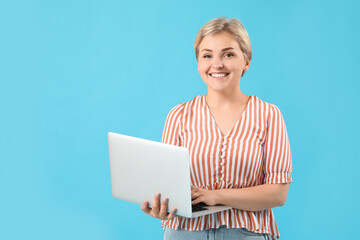 Wall Mural - Happy young female programmer with laptop on blue background