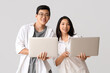 © Pixel-Shot - Young Asian friends with laptops on light background