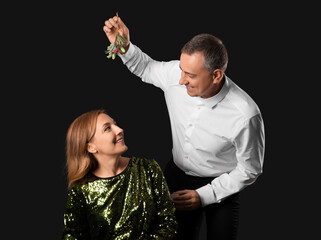 Poster - Mature couple with mistletoe branch on dark background