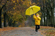 © somemeans - Child happily runs through the autumn park. Kid jumps up with large yellow umbrella in hands.