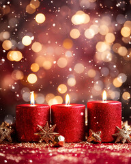 Christmas red candles, new year burning candle on magic light bokeh background with copy space. Winter holidays festive greeting card.