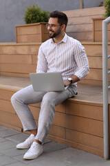 Poster - Handsome young man using laptop on bench outdoors