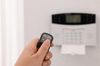 Home security system. Woman using alarm key fob indoors, closeup