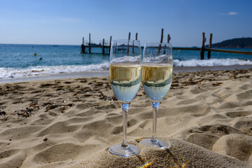 Summer time in Provence, two glasses of cold champagne cremant sparkling wine on famous Pampelonne sandy beach near Saint-Tropez in sunny day, Var department, France