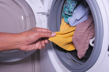 Wall Mural -  men hand putting a cloths in a washing machine.