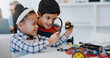 © Clement C/peopleimages.com - Students magnifying glass and classroom for robotics, education and learning for technology, science and school project. Kindergarten, children or thinking with kids, study and inspection research