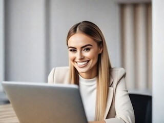 a young smiling beautiful woman is working at a laptop in the office