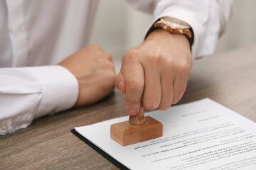 Poster - Man stamping document at wooden table, closeup