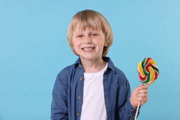 Wall Mural - Happy little boy with colorful lollipop swirl on light blue background