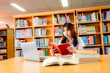 © atsarapong - Asian female university student sitting at table with books and laptop in library
