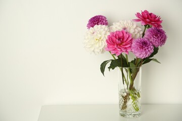 Sticker - Bouquet of beautiful Dahlia flowers in vase on table near white wall, space for text