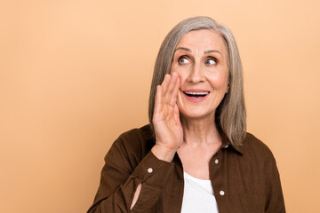 Poster - Portrait of excited positive lady arm near mouth communicate look empty space isolated on beige color background