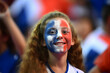 A teenage girl with the French flag painted on her face cheers for the French team at the stadium during the 2024 Summer Olympics in Paris