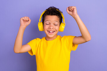 Sticker - Photo portrait of nice young pupil boy headphones listen music raise hands wear yellow garment isolated on purple color background