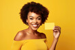 © Rafa Fernandez - Winking woman holding credit card with hand isolated on yellow colored background. AI Generative