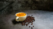 A cup coffee of espresso with coffee golden crema and coffee beans on a grey background.