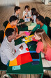 © Jose Calsina - Vertical high angle view of a big group of multiracial teenage students working on university assignment homework project on high school library. Teamwork of diverse young classmates studying together